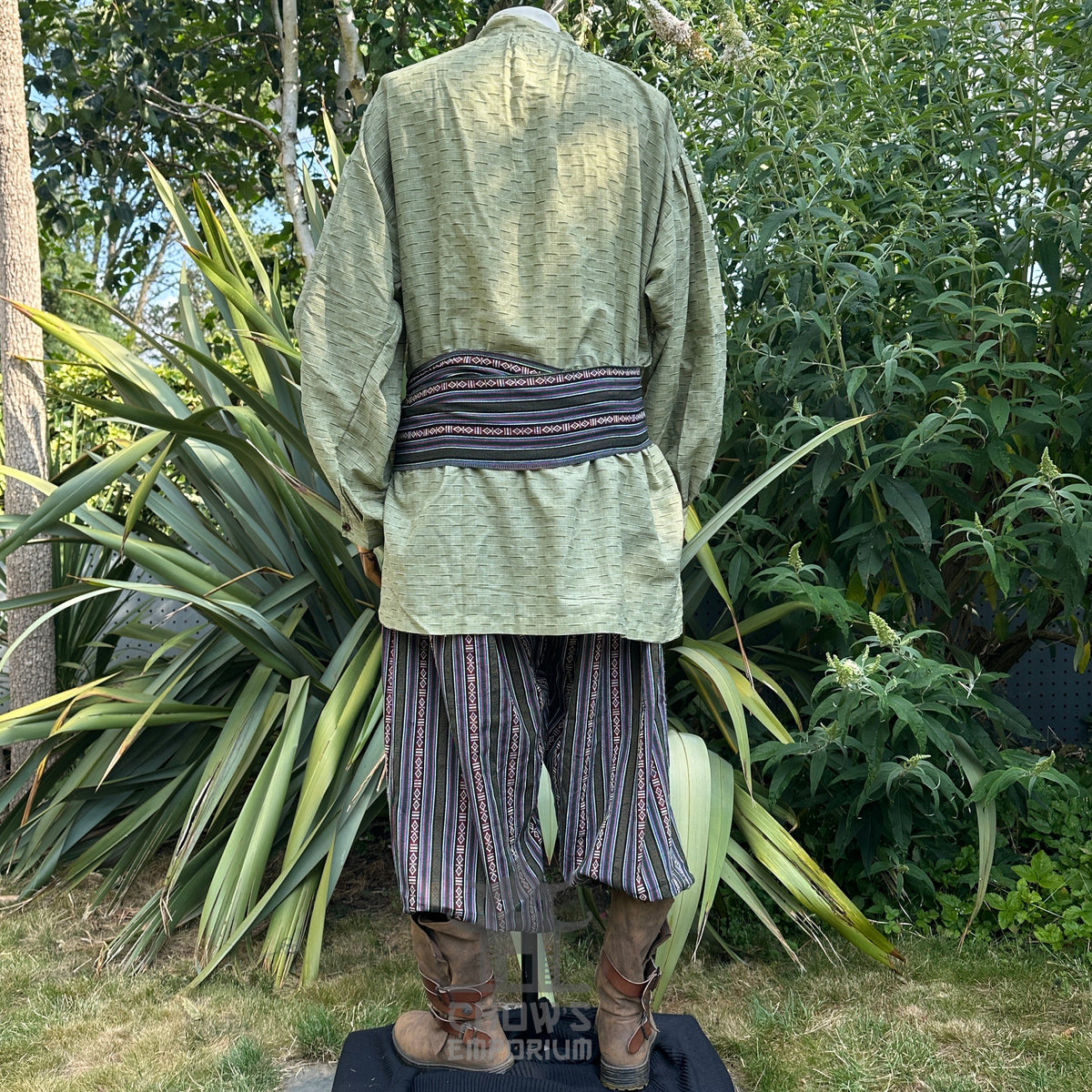 Medieval LARP outfit back view, featuring a green shirt, patterned trousers, matching sash.