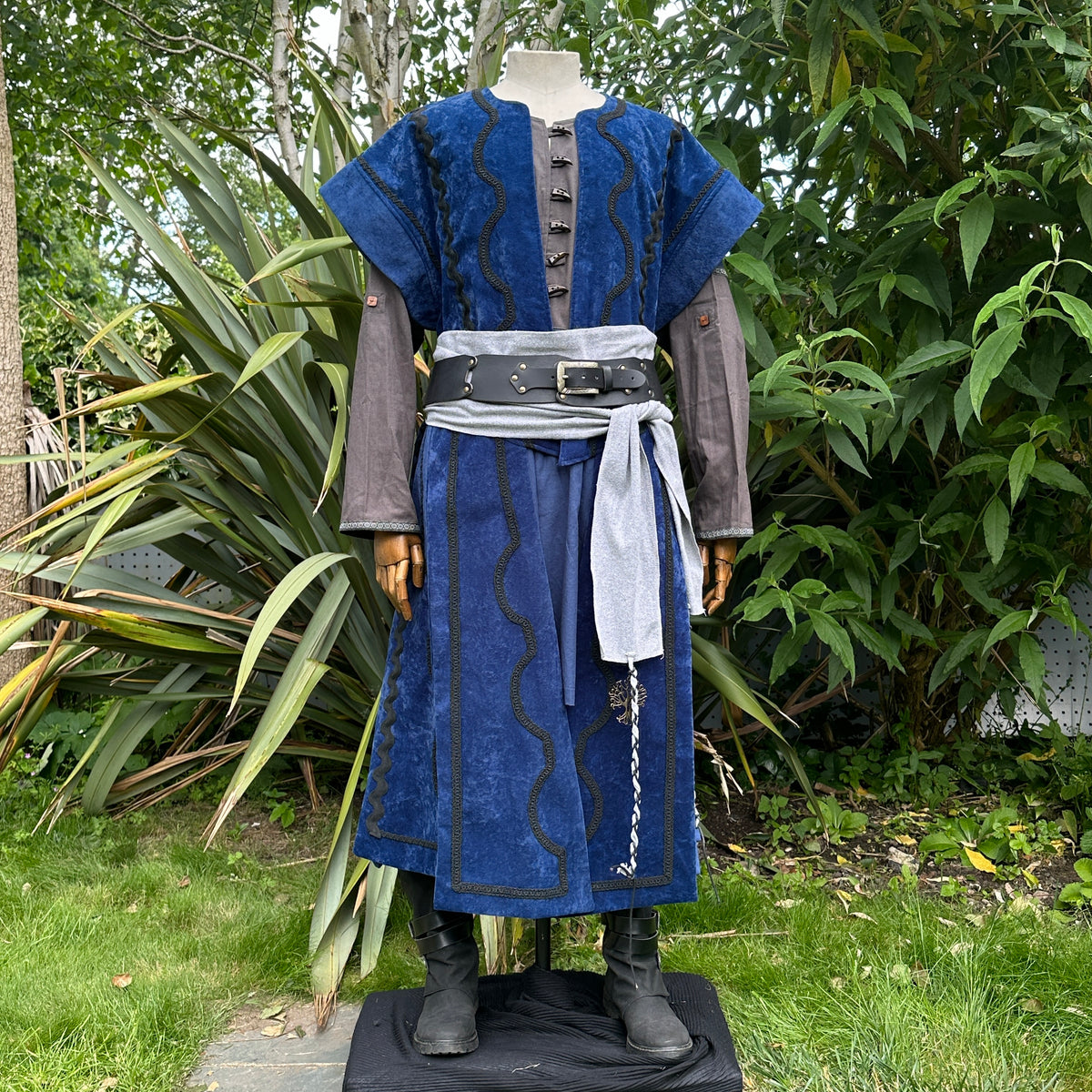 Blue medieval LARP outfit with waistcoat, grey sash, and arm wraps.