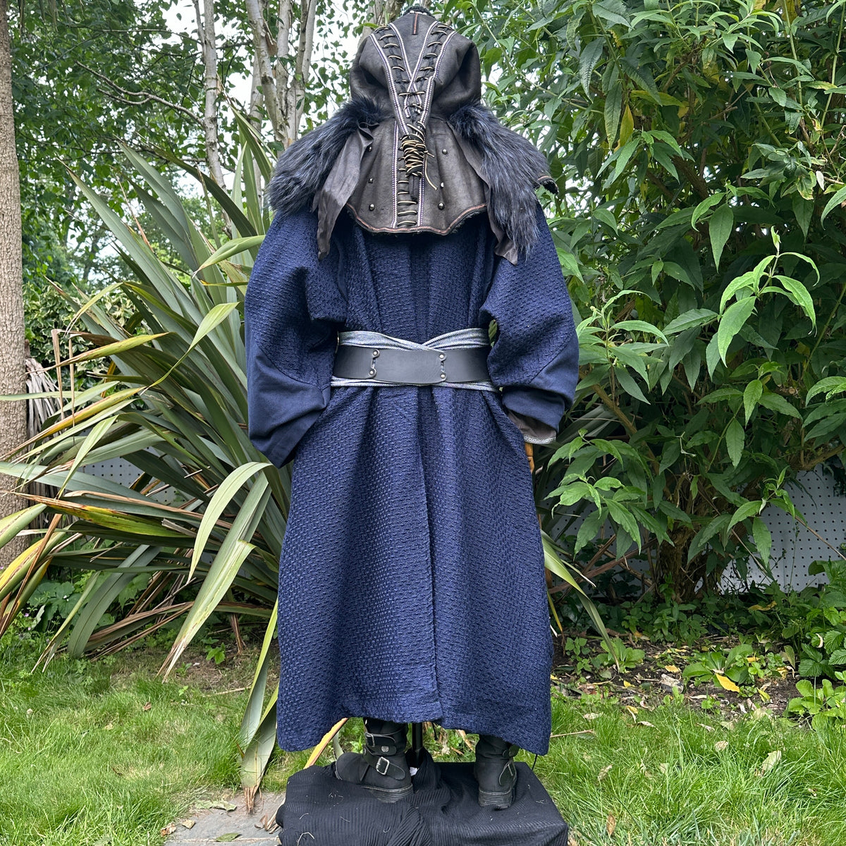 Blue medieval LARP robe with ornate hood, silver belt, back view amidst greenery.