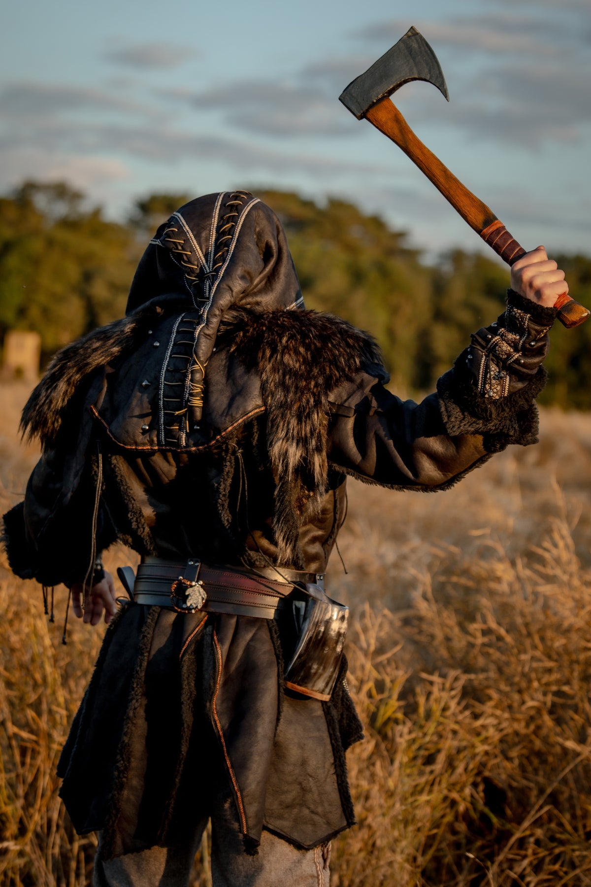 Medieval LARP costume back view featuring a black faux leather jacket, hood and vambraces.