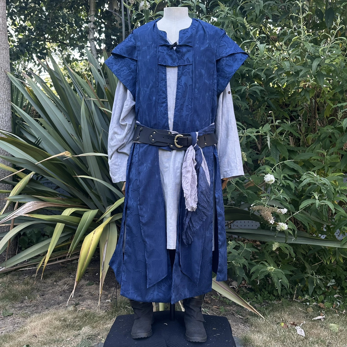 Blue panelled waistcoat with the hood down and a sash at the waist, front view. Shirt and belt sold separately.