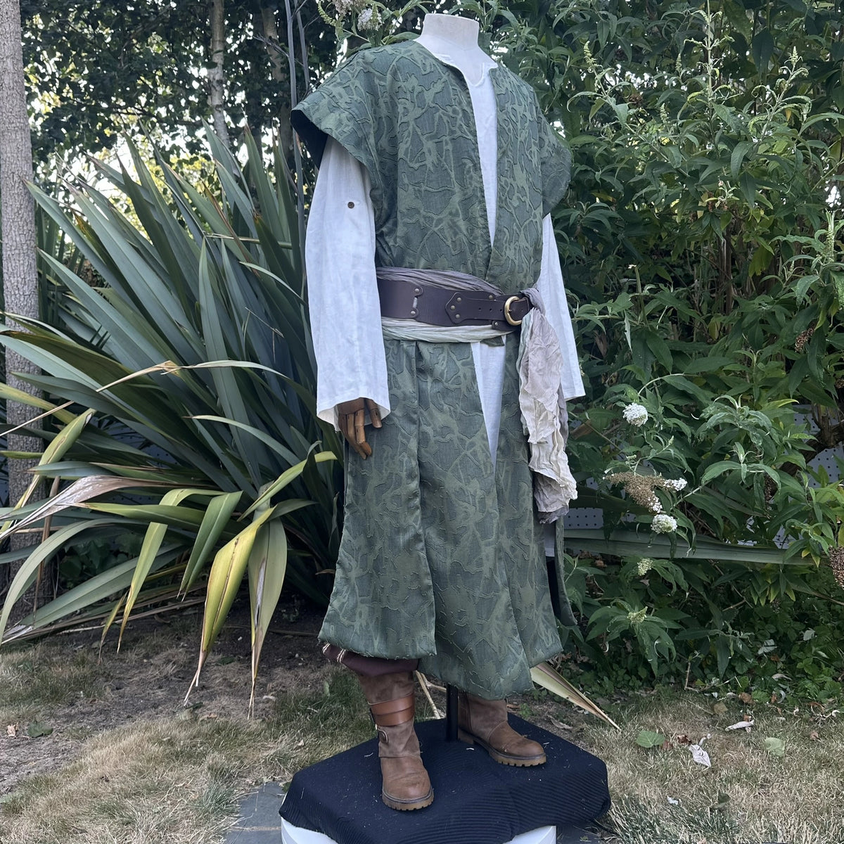 Green panelled waistcoat and hood set, hood down with a leather belt, three-quarter view. Belt sold separately.