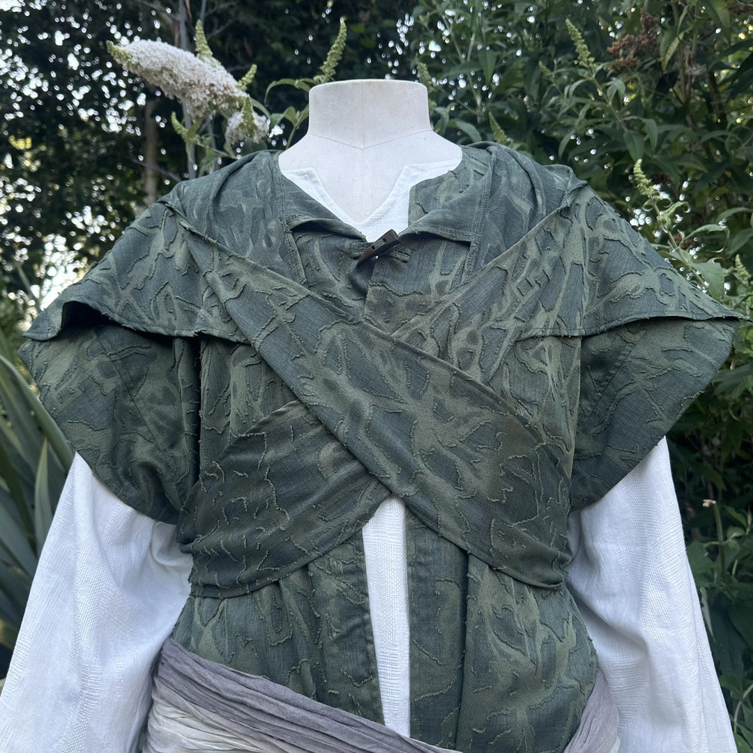 Close detail of the distressed green panelling across the chest of the waistcoat and hood set.