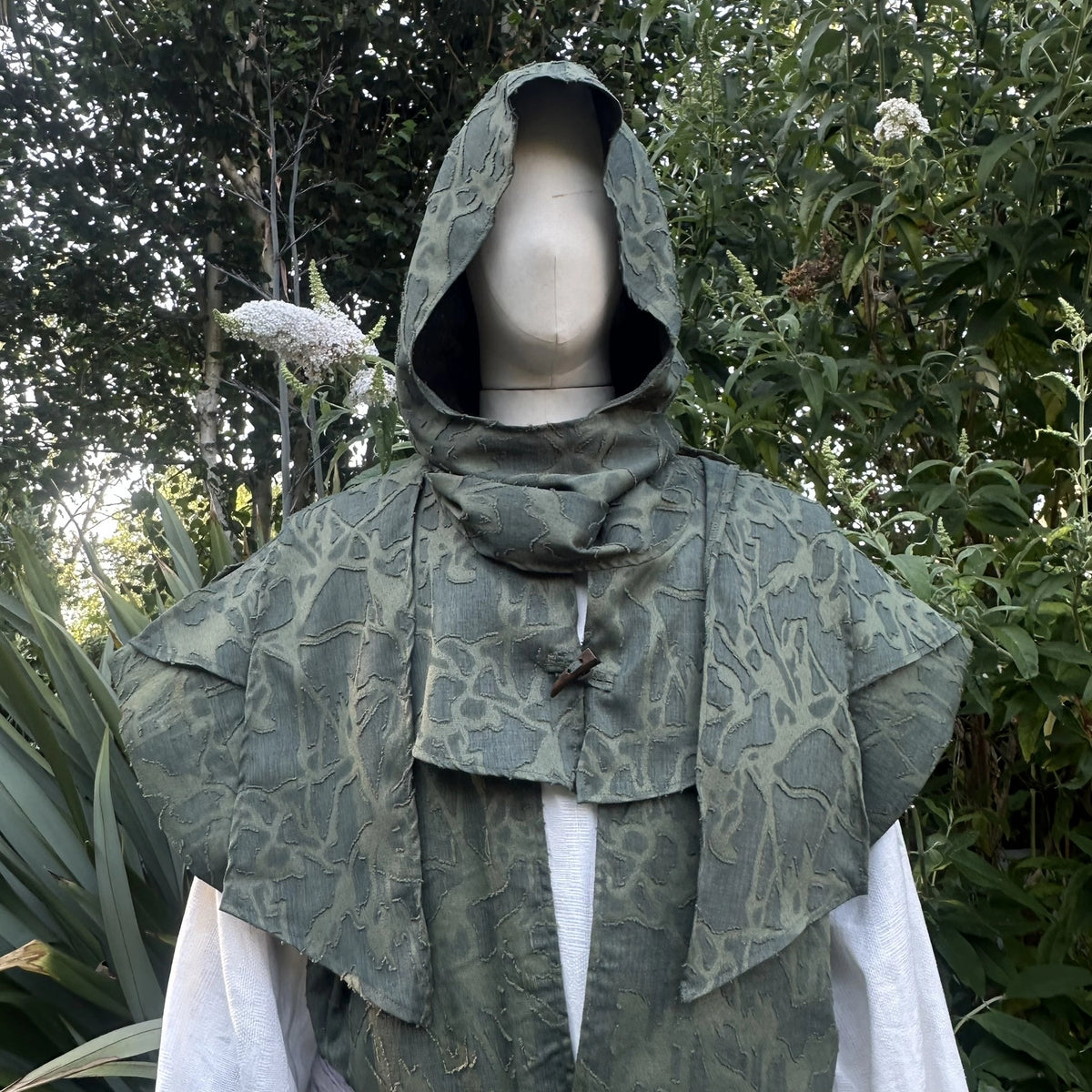 Green waistcoat and hood set with the hood worn up and draped over the shoulders, front view.