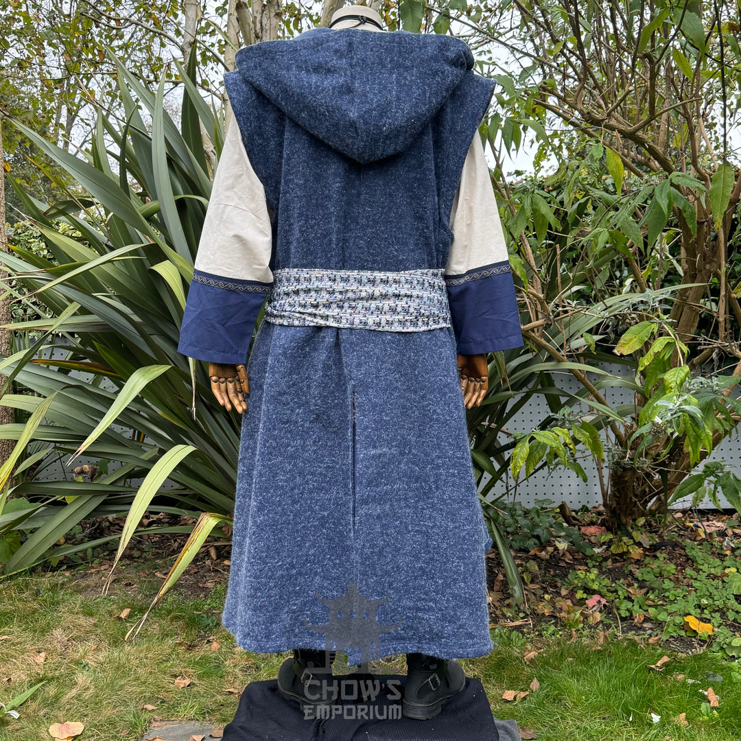 Long blue hooded robe with white and blue patterned sash on mannequin against a natural background.