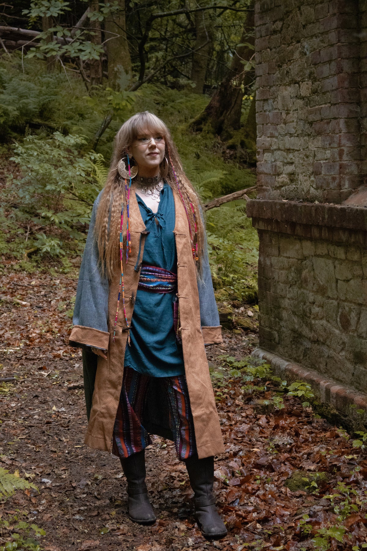 Teal pirate coat in medieval LARP woodland scene, side view of boots.