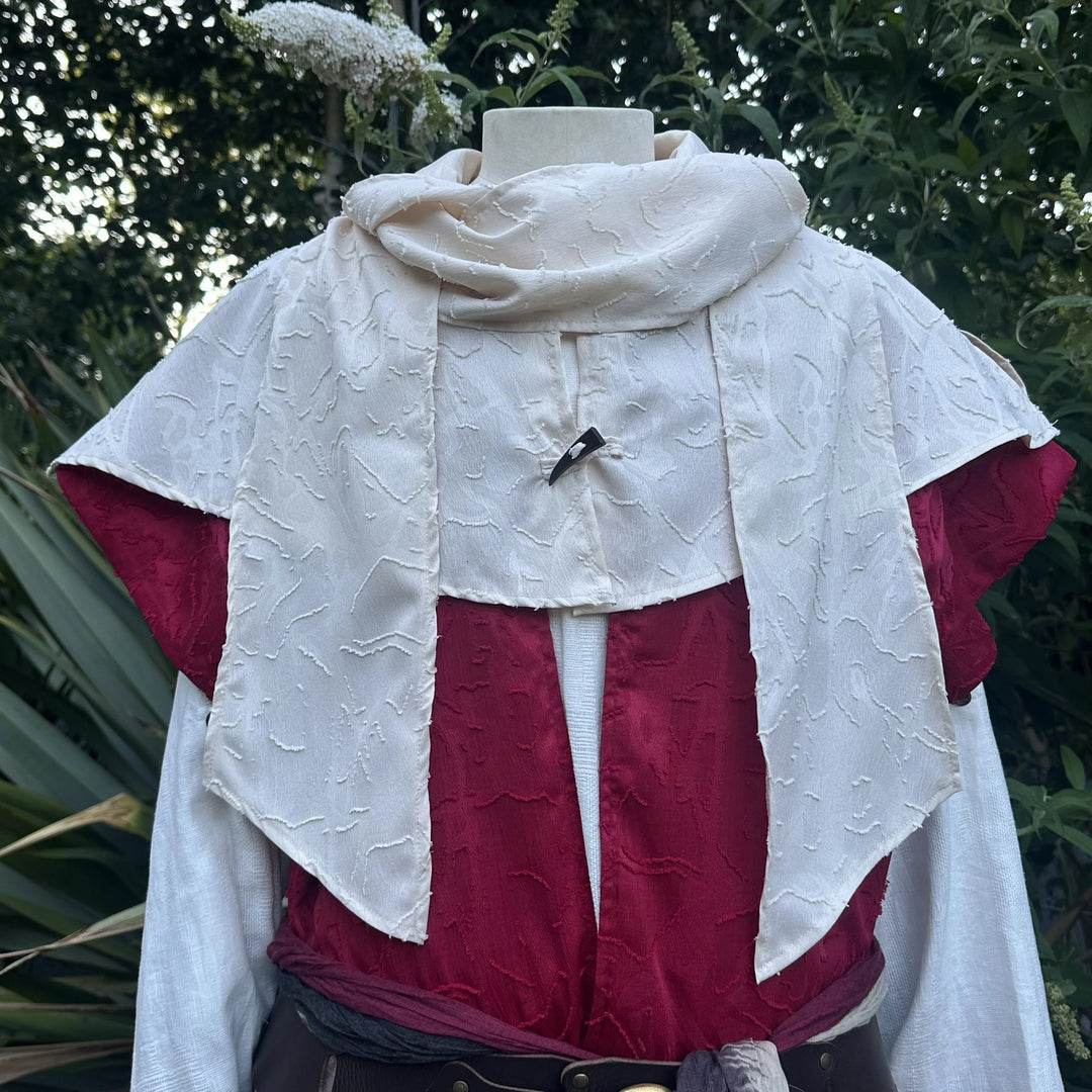 Close view of the cream hood gathered as a cowl at the neck over the red layer.