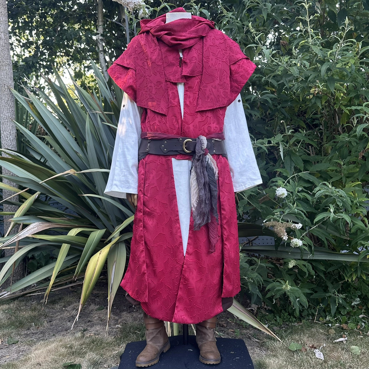 Red panelled waistcoat with the hood down as a cowl at the neck, front view. Shirt and belt sold separately.