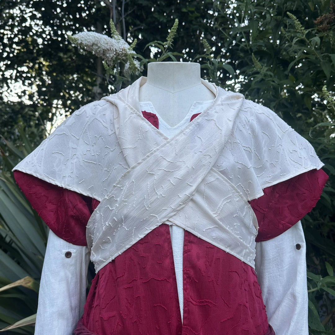 Close detail of the cream waistcoat crossed over the chest above the red layer.