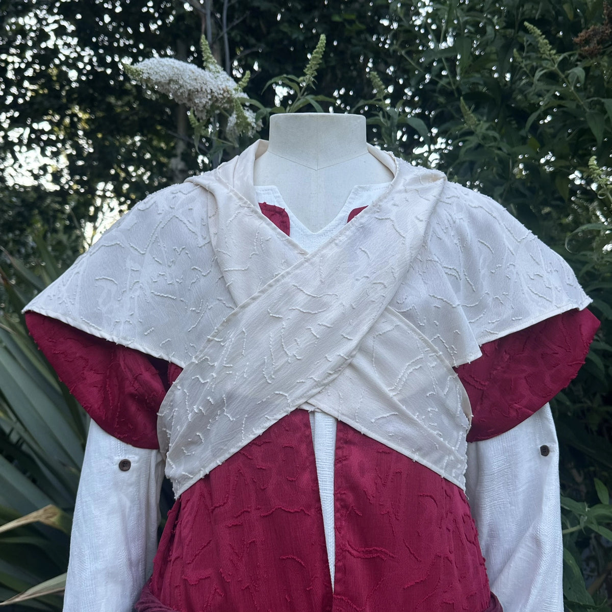 Close detail of the cream waistcoat crossed over the chest above the red layer.