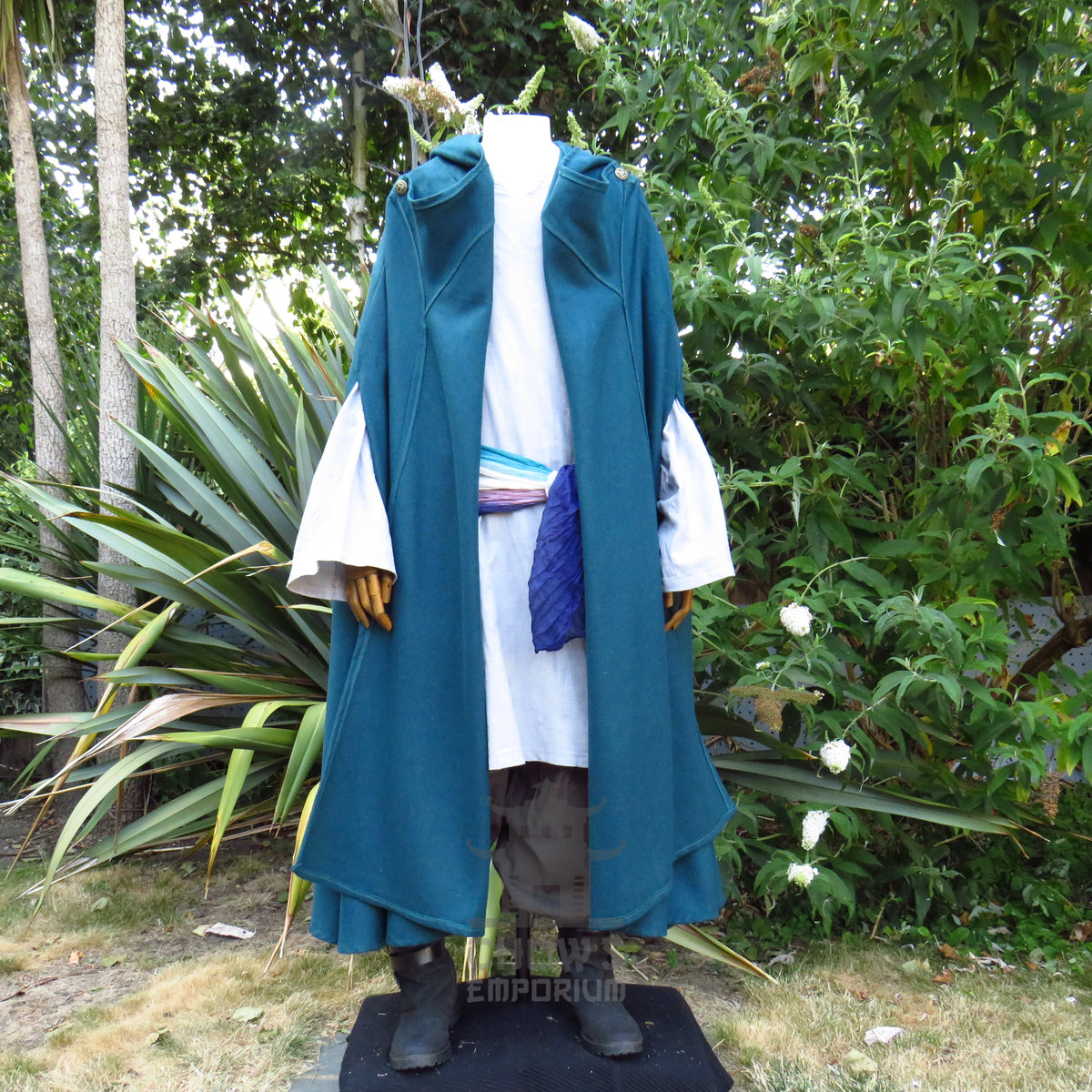 Teal hooded cloak styled open over a tunic with a sash at the waist, other pieces sold separately