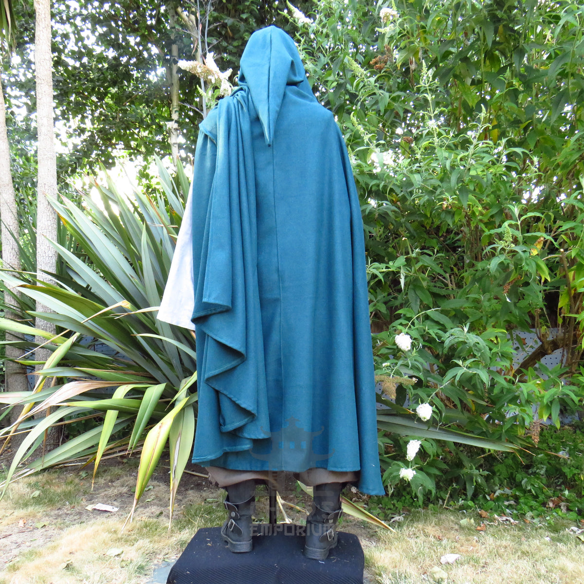 Three-quarter view of the teal wool cloak, hood up, showing the drape at the side