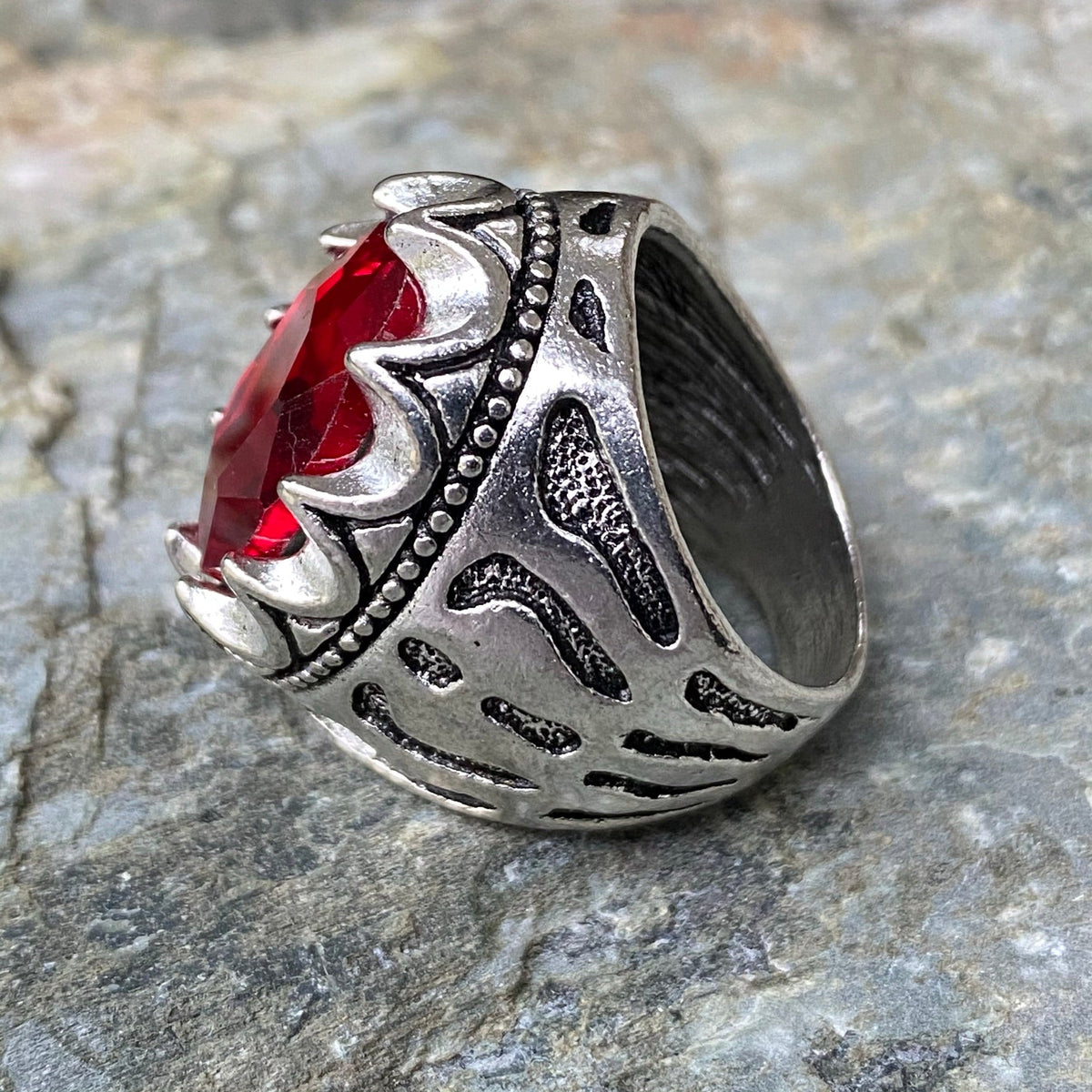 Silver ring with ornate engravings and red gem, angled for medieval LARP.