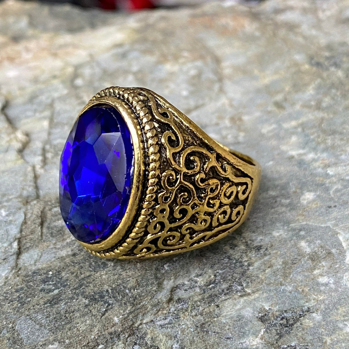 Medieval LARP gold ring with ornate filigree and vibrant blue gemstone.