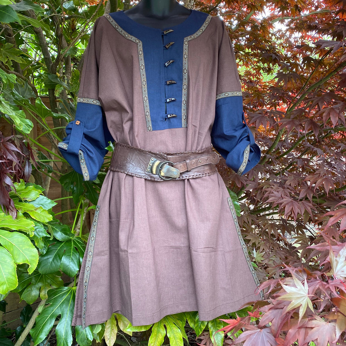 Medieval LARP tunic in garden, brown-blue, front view, leather belt detail.