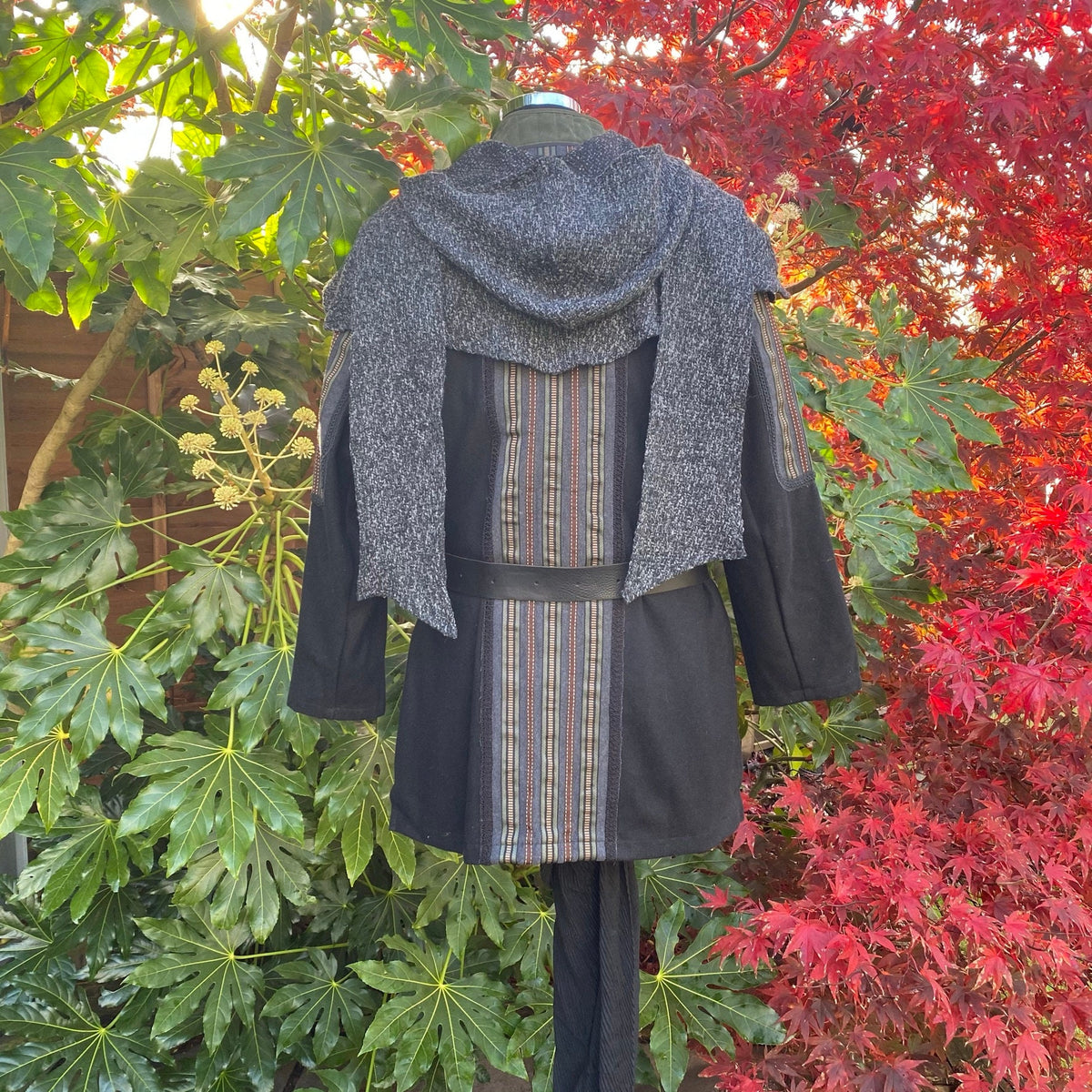 Back view of LARP druid tunic with striped center and hood, autumn foliage backdrop.