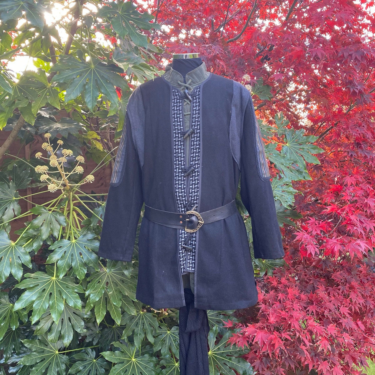 Medieval LARP tunic with belt, front view, red foliage background.