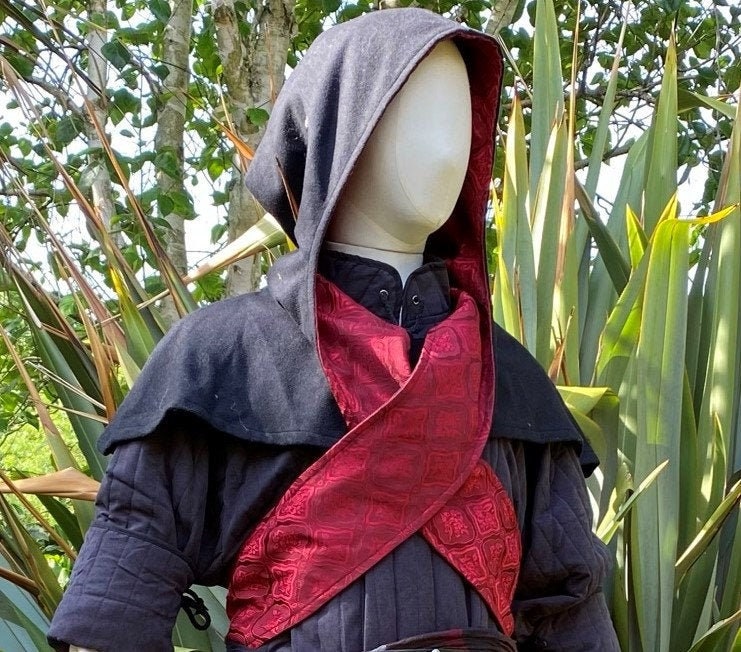 This LARP Hood is Black with a Wrap Around extention. This Viking Scarf Hood is made of Faux Suede Effect, and is Water Resistant and Warm. It has an interior Elaborate Red Satin Pattern, perfect for your LARP Character and LARP Costume, Cosplay Event, and Ren Faire.