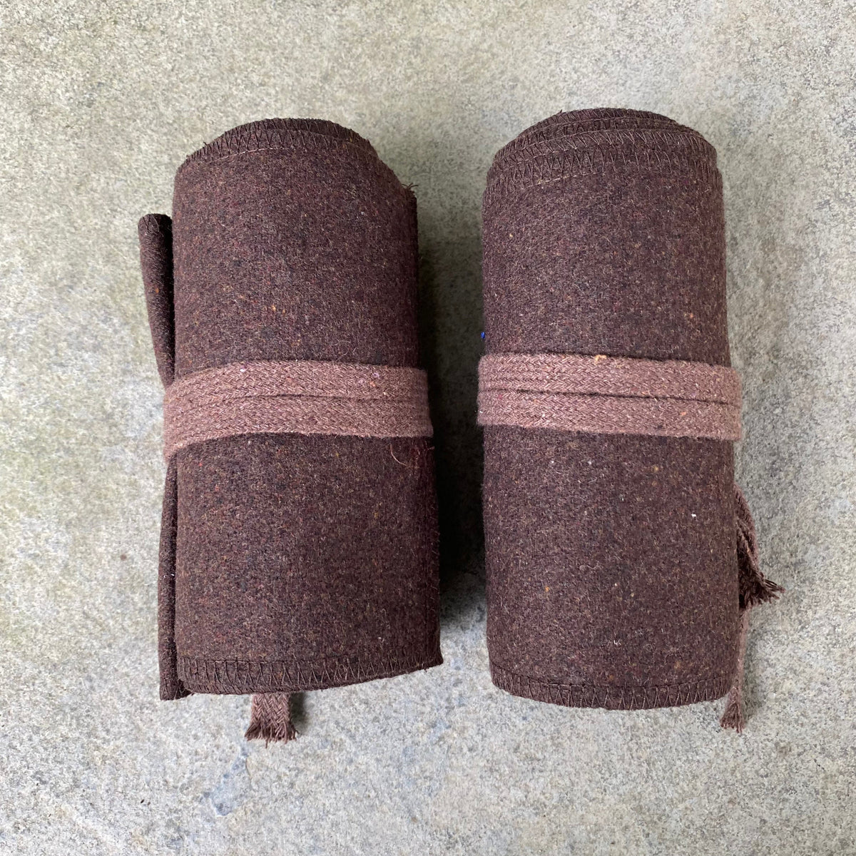 Two rolled brown wool leg wraps on stone for LARP.