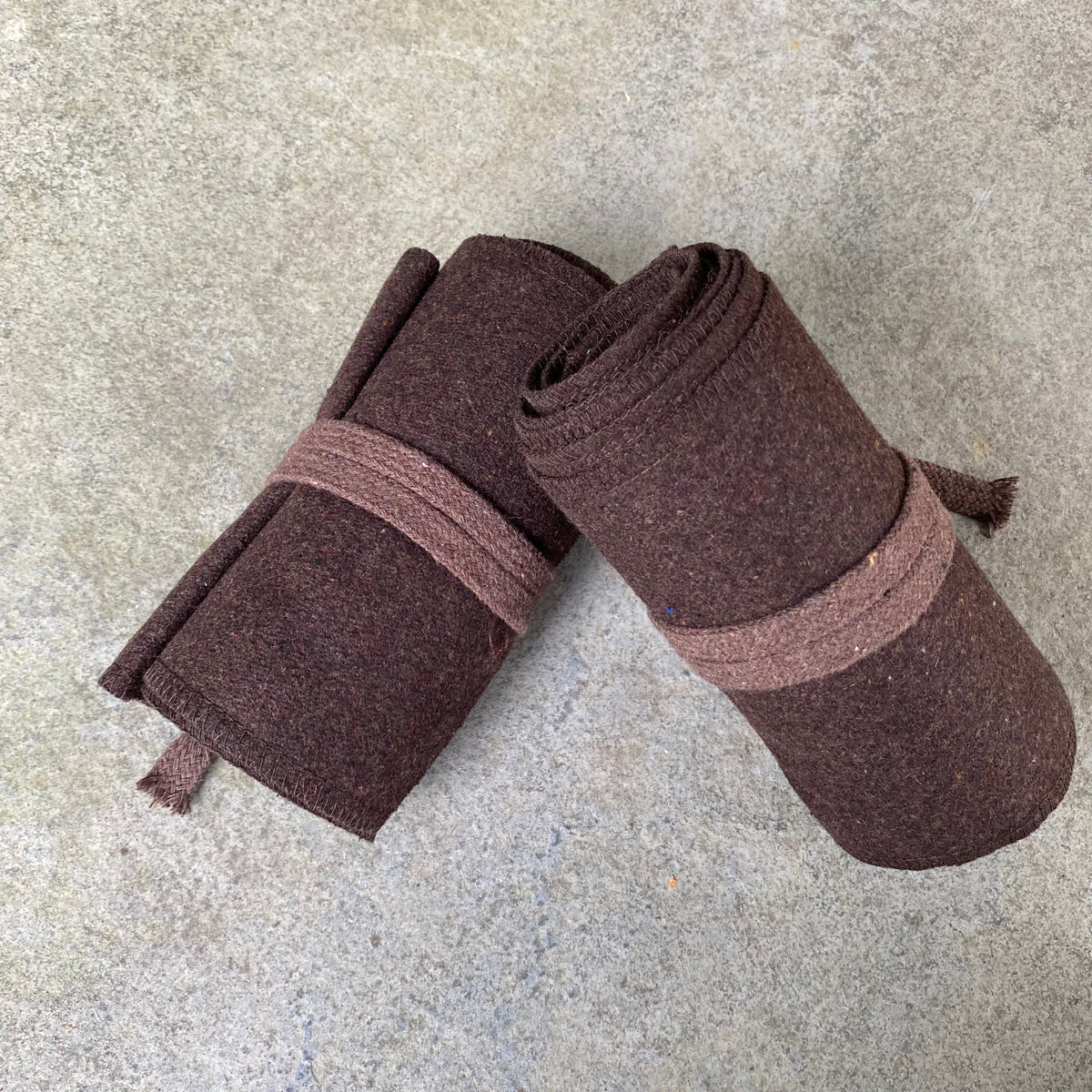 Rolled brown wool leg wraps on a stone background for medieval LARP.
