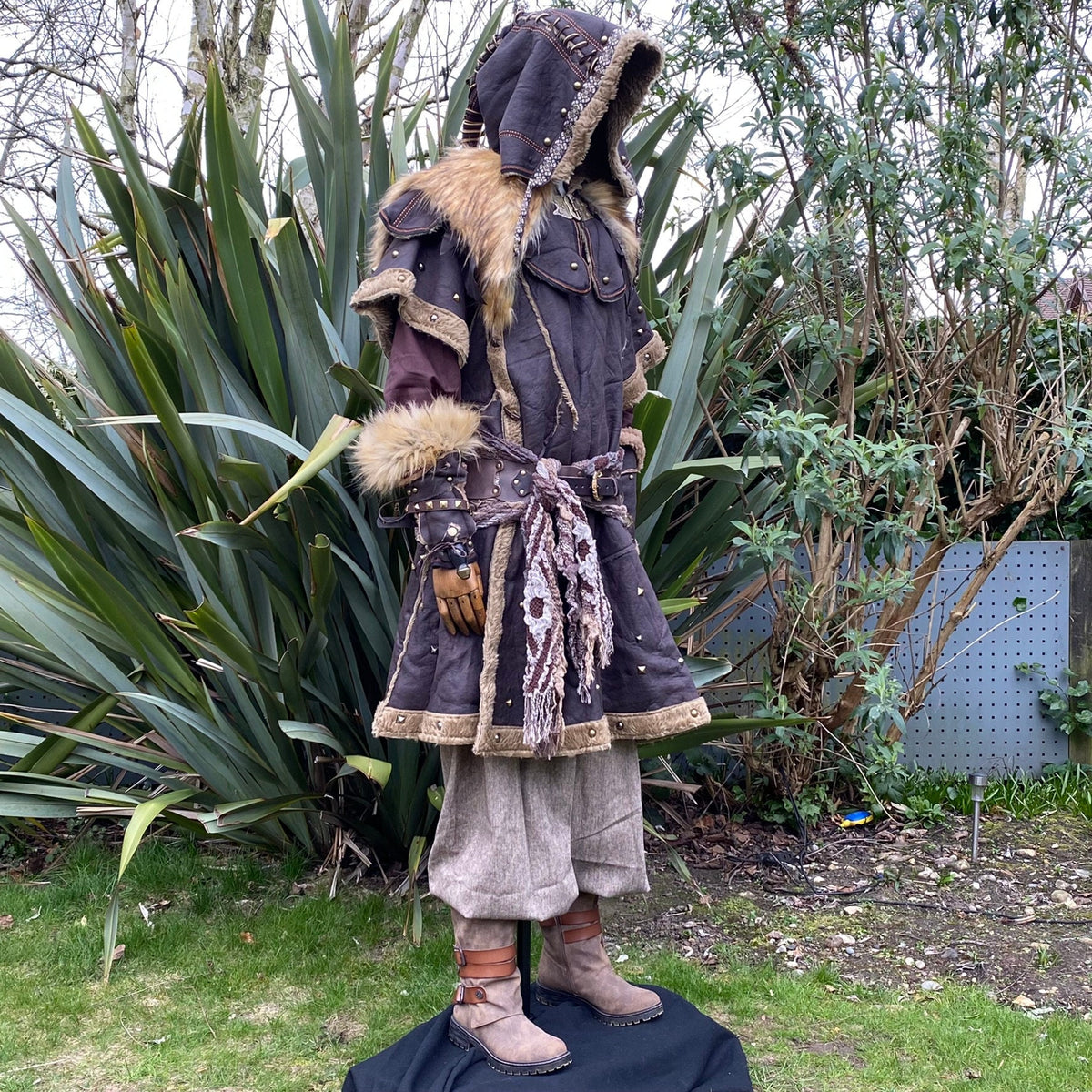 Side view of a LARP costume; hooded tunic, fur trim, detailed vambrace.