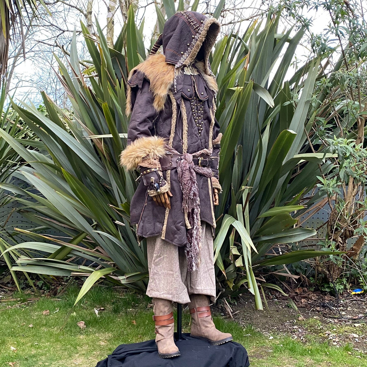 Medieval LARP costume side view featuring a brown faux leather jacket, hood and vambraces, shirt.