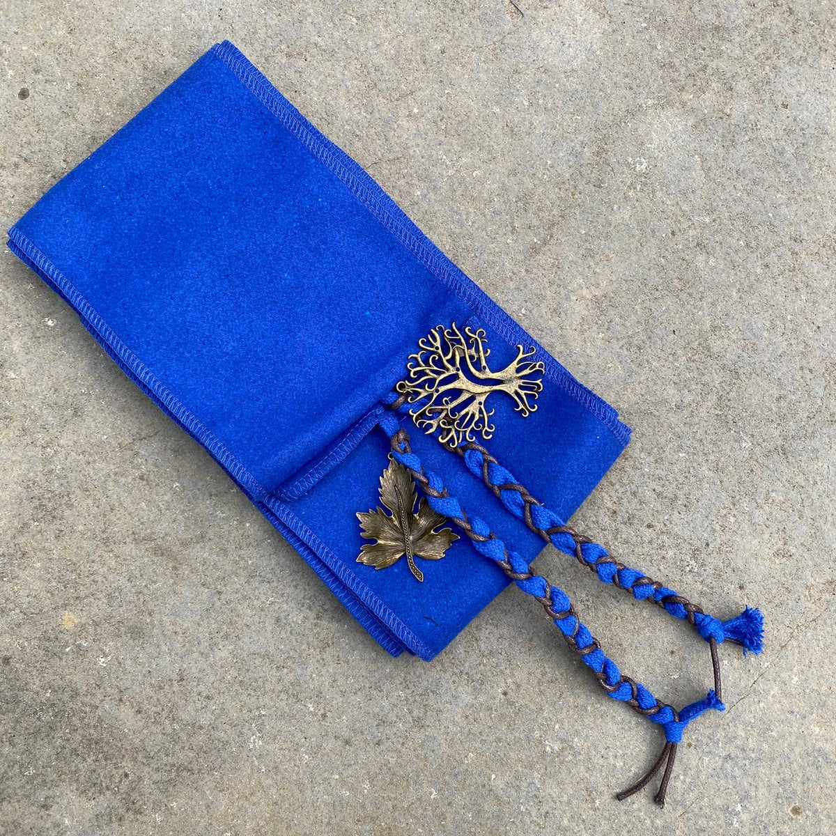 Blue wool LARP sash with tree and leaf charms, braided ties visible.