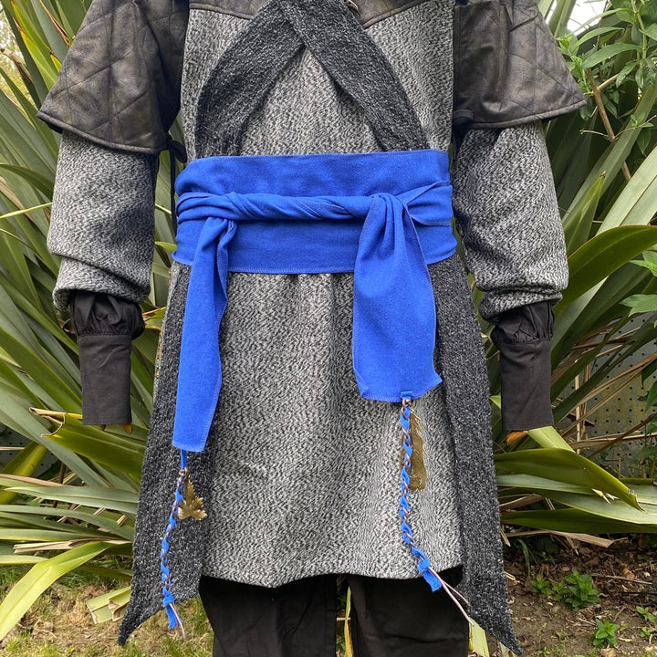 A Blue Wool LARP Sash. The Viking Sash is a Woollen sash that works well by itself, or underneath a LARP Belt. The LARP Sash is 300cm long, and can comfortably wrap around you. The Medieval Sash has a decorated metal accessories that adds to your LARP Character, Cosplay, or Ren Faire event.