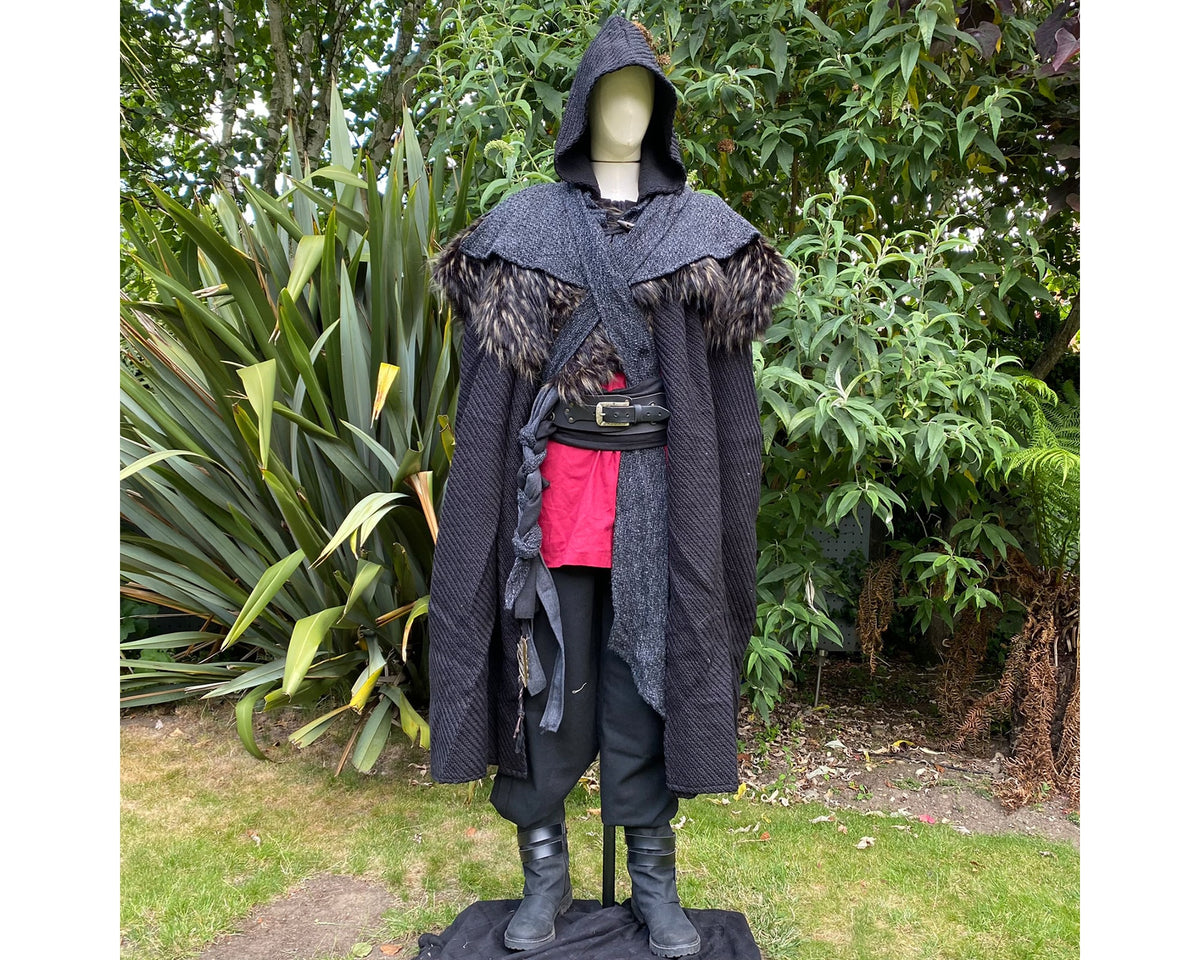 LARP Viking outfit on mannequin, lush garden, black cloak, red shirt.
