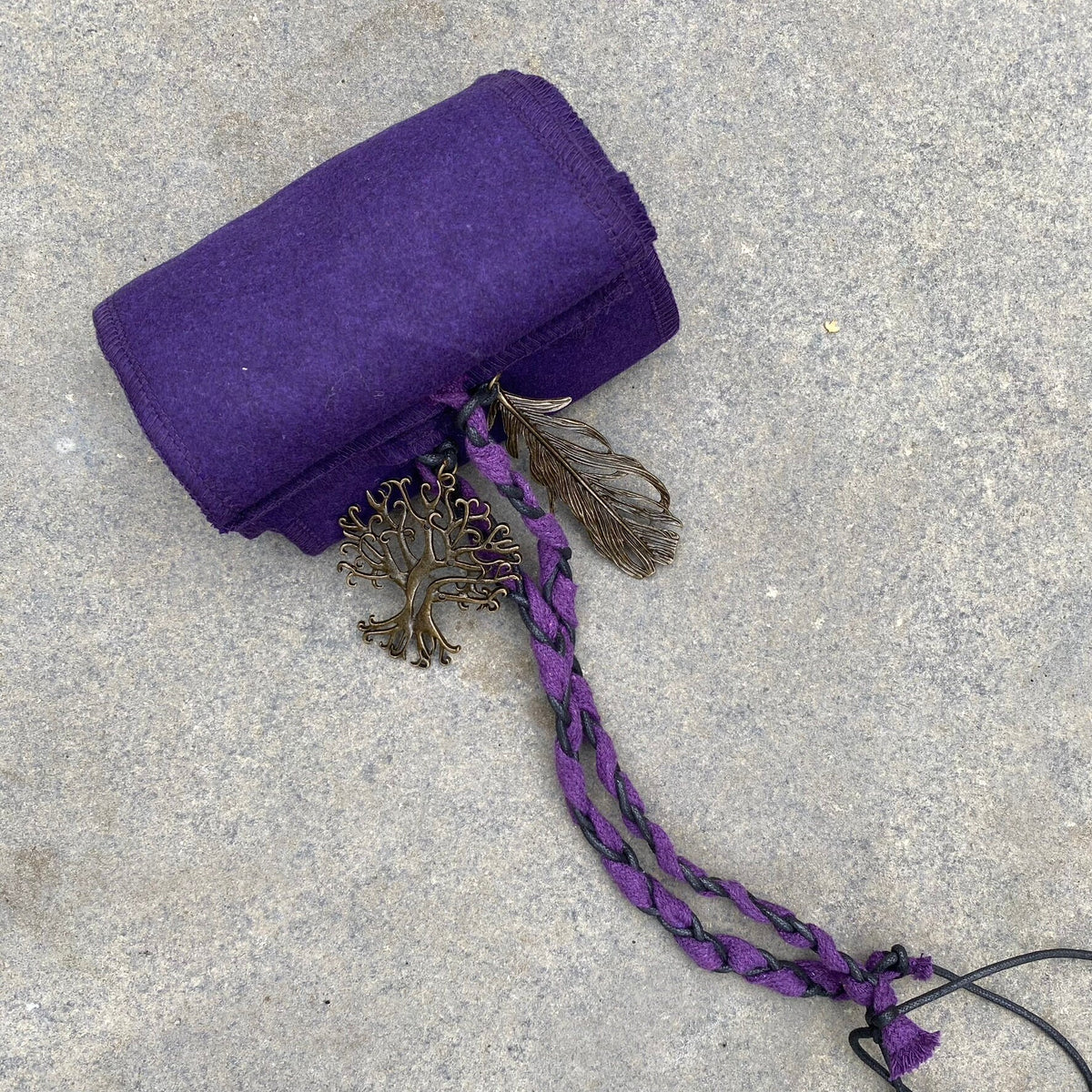 Purple wool LARP sash with braided cord and tree decoration on stone.
