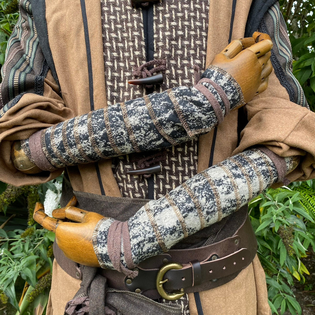 Brown wool arm wraps with black pattern for medieval LARP costume close-up.