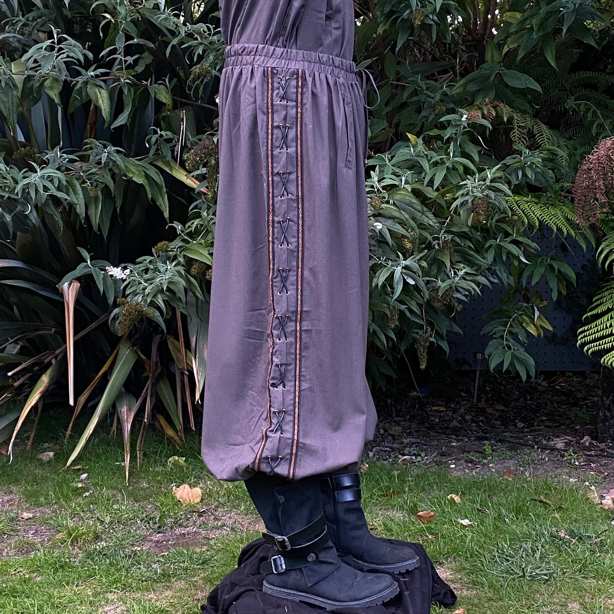 Side view of grey LARP pants with intricate side lace by greenery.