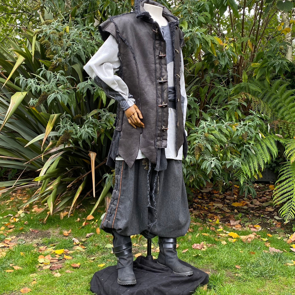 Medieval LARP outfit side view, featuring a black waistcoat, grey cotton shirt, trousers and sash.