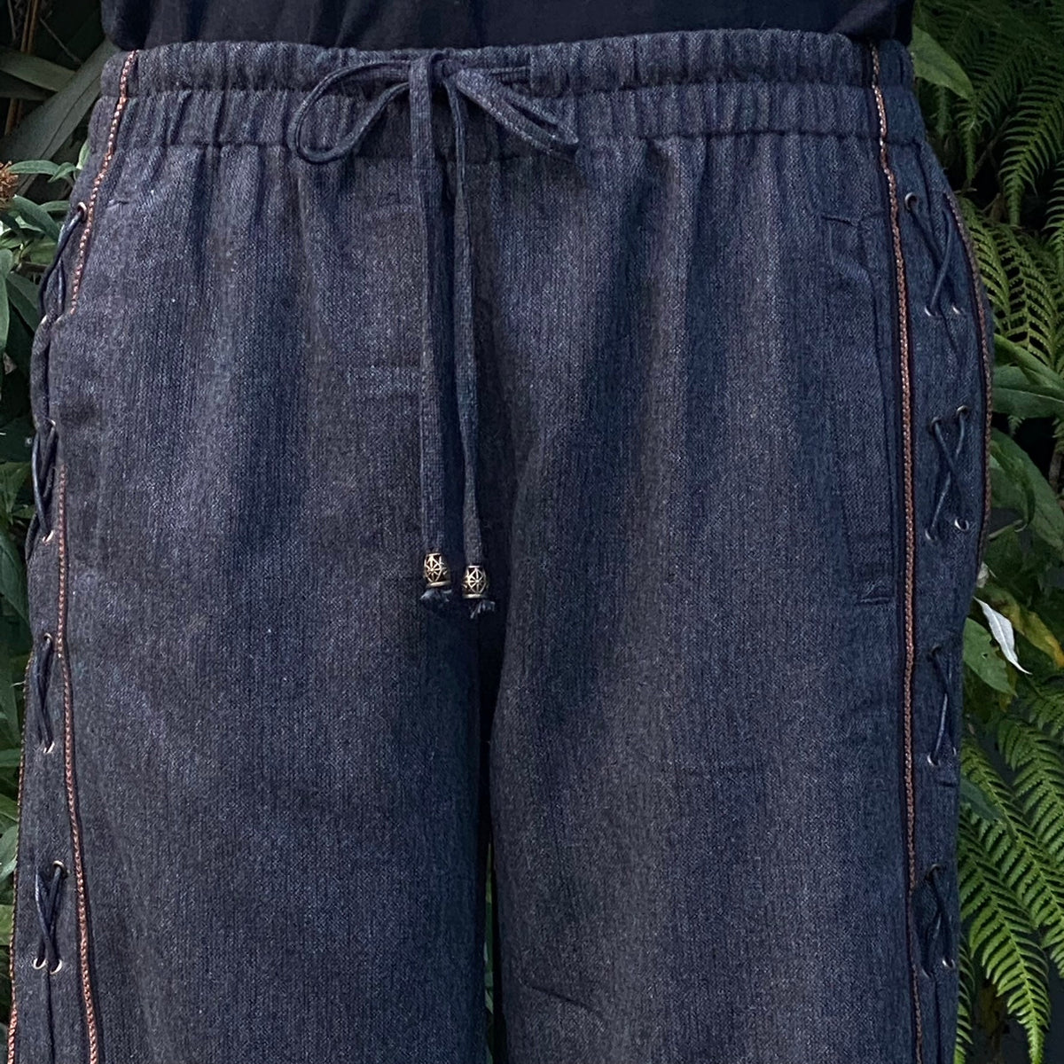 Close-up detail of faux leather side lacing and co-ordinating braided trim on wool fabric.