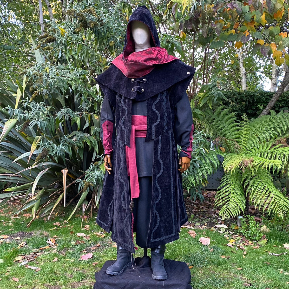 Black and red LARP costume in garden; suede waistcoat; hood up.