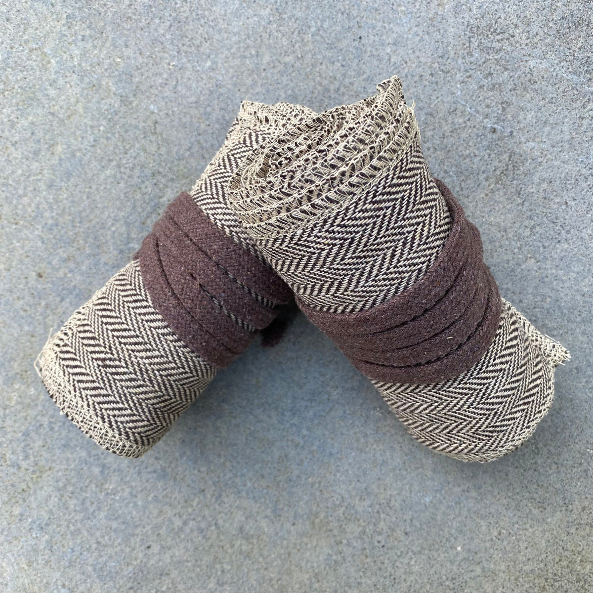 Rolled herringbone wool leg wraps on stone surface for medieval LARP.
