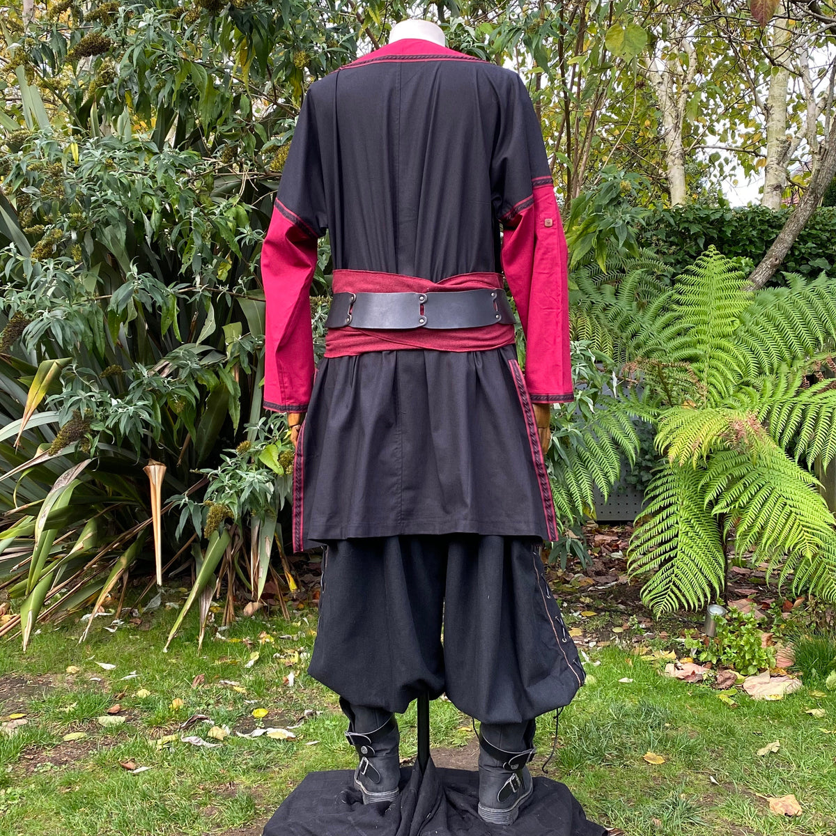 Back view of LARP medieval outfit, black-red tunic, pants, and sash.