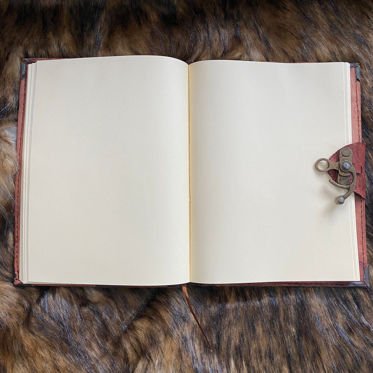 Open leather journal on fur, showcasing medieval metal clasp for LARP.