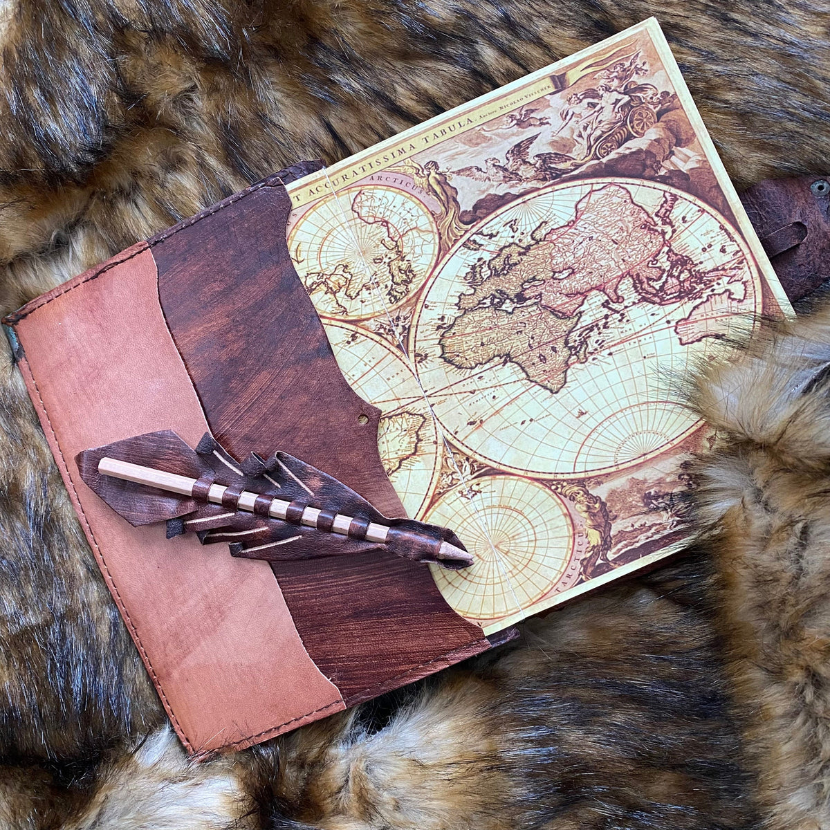 Medieval leather journal with map design, quill pocket on fur backdrop.