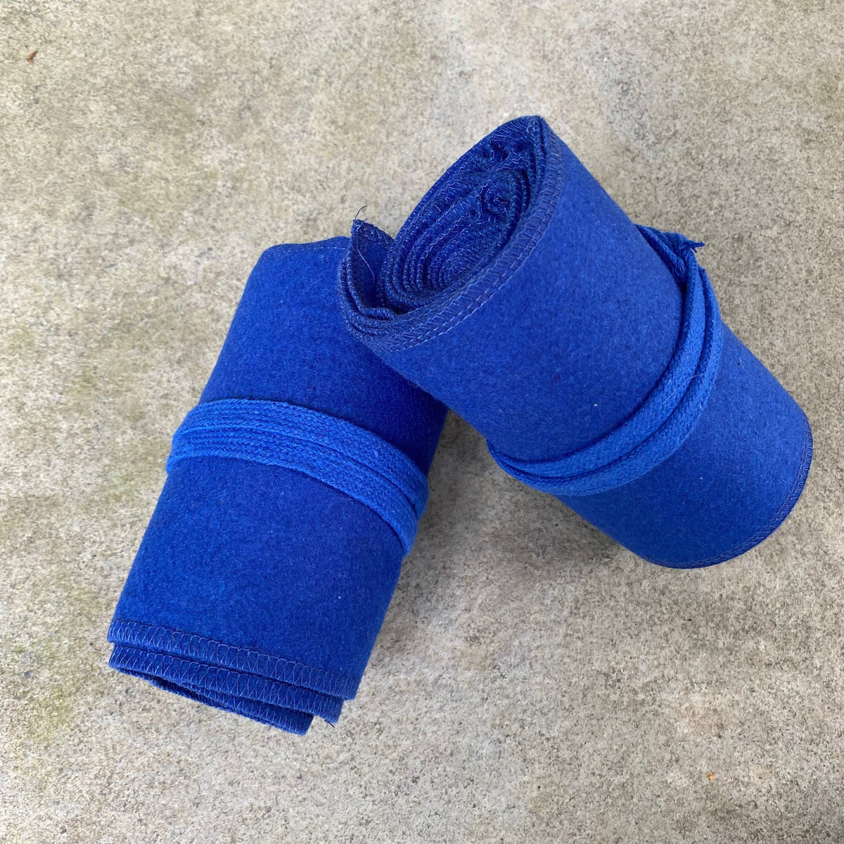 Two rolled blue wool leg wraps for LARP on concrete background.