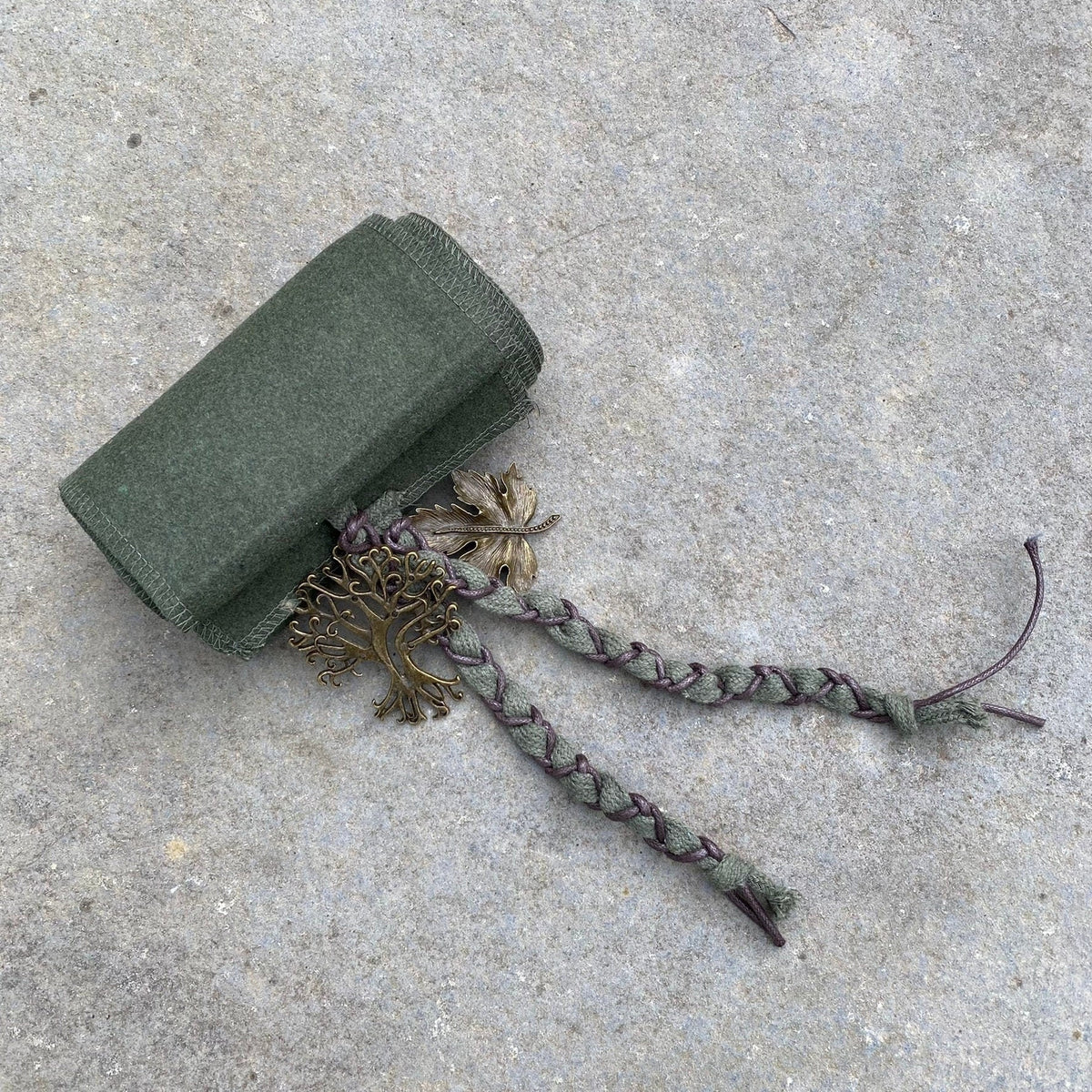 Braided LARP sash with tree charm on grey background, green wool.