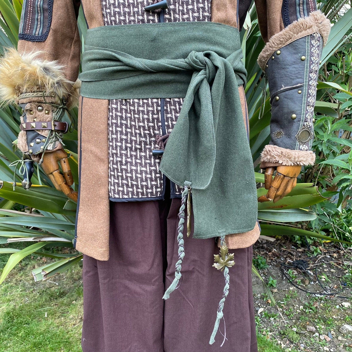 Green wool sash tied on medieval outfit with braided ends and leaf charm.