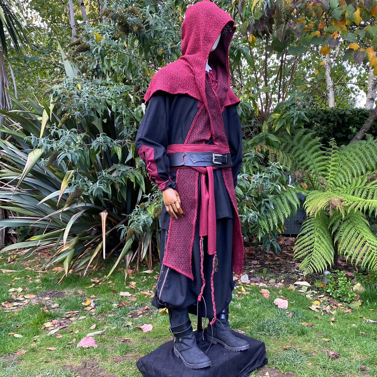 Medieval LARP outfit with red hood and sash in a garden setting, side view.