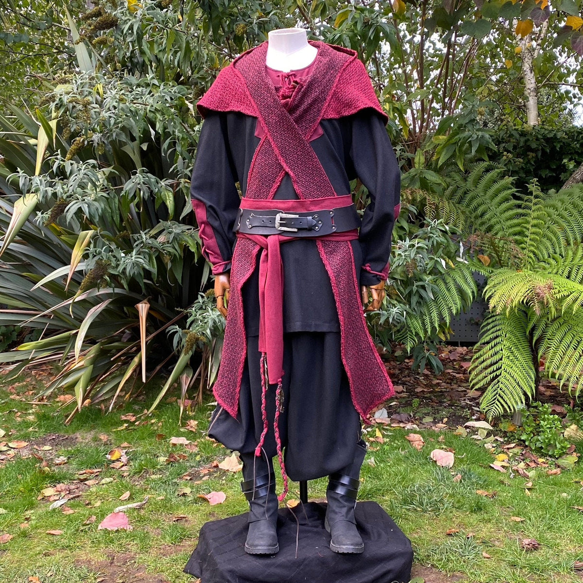 Medieval LARP attire displayed outdoors; black-red ensemble with belt detail.