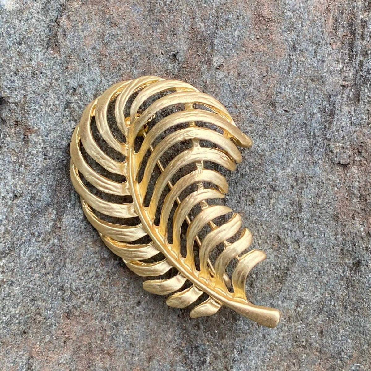 Gold fern brooch on stone, side view for LARP.