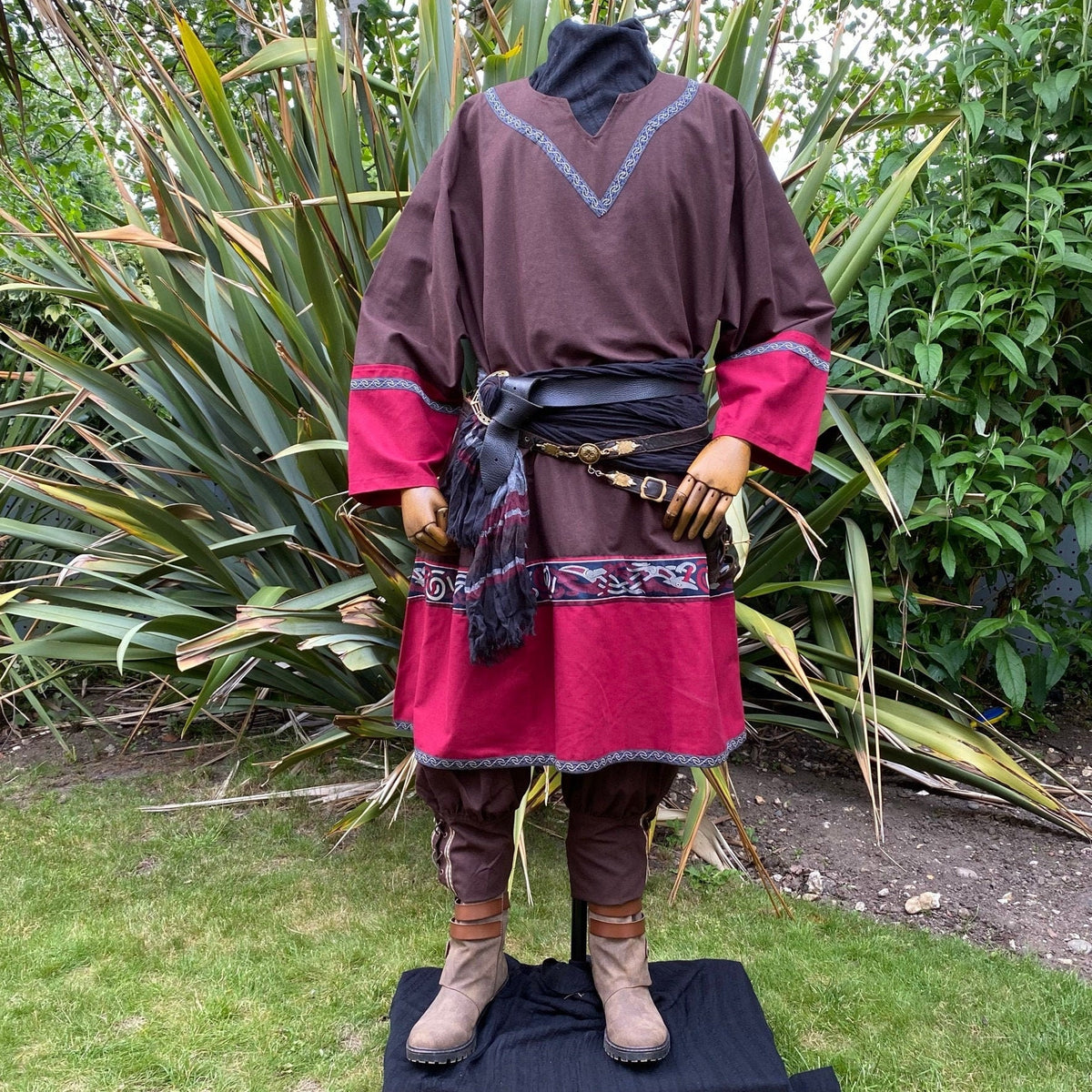 Brown and red medieval LARP tunic, hood, and pants on a greenery backdrop.