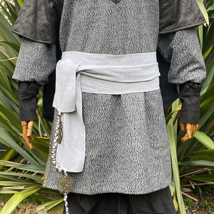A Light Grey Wool LARP Sash. The Viking Sash is a Woollen sash that works well by itself, or underneath a LARP Belt. The LARP Sash is 300cm long, and can comfortably wrap around you. The Medieval Sash has a decorated metal accessories that adds to your LARP Character, Cosplay, or Ren Faire event.