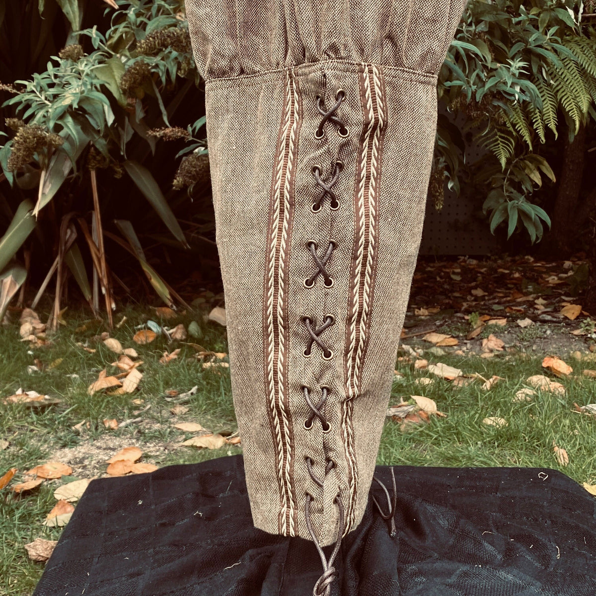 close up of braiding and lacing detail on brown wool pants.