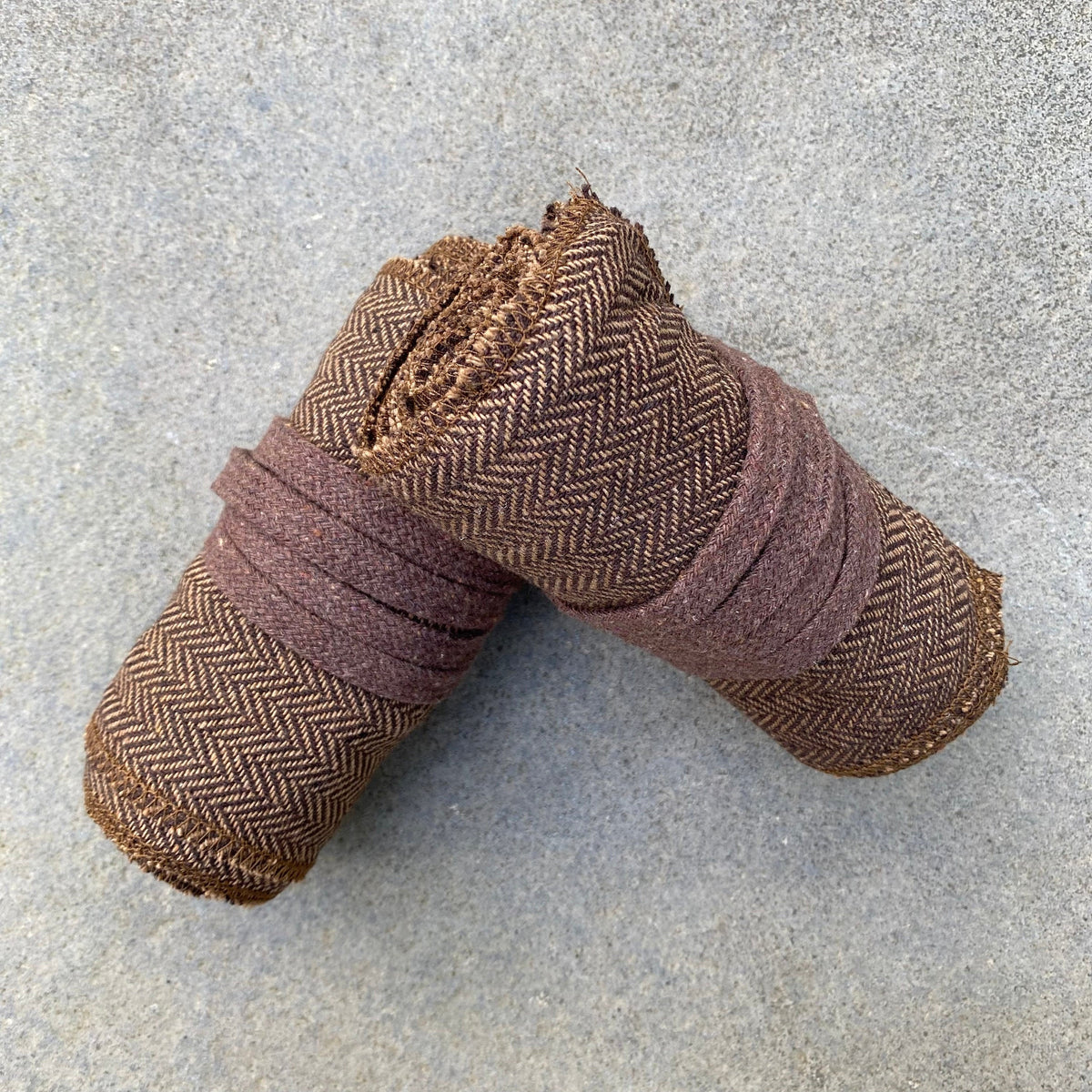 Brown herringbone wool leg wraps rolled for medieval LARP.