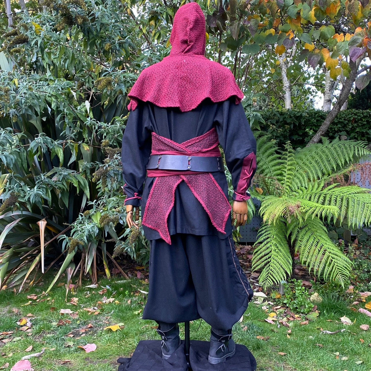 Side view of red hooded LARP outfit with sash and layered robe.